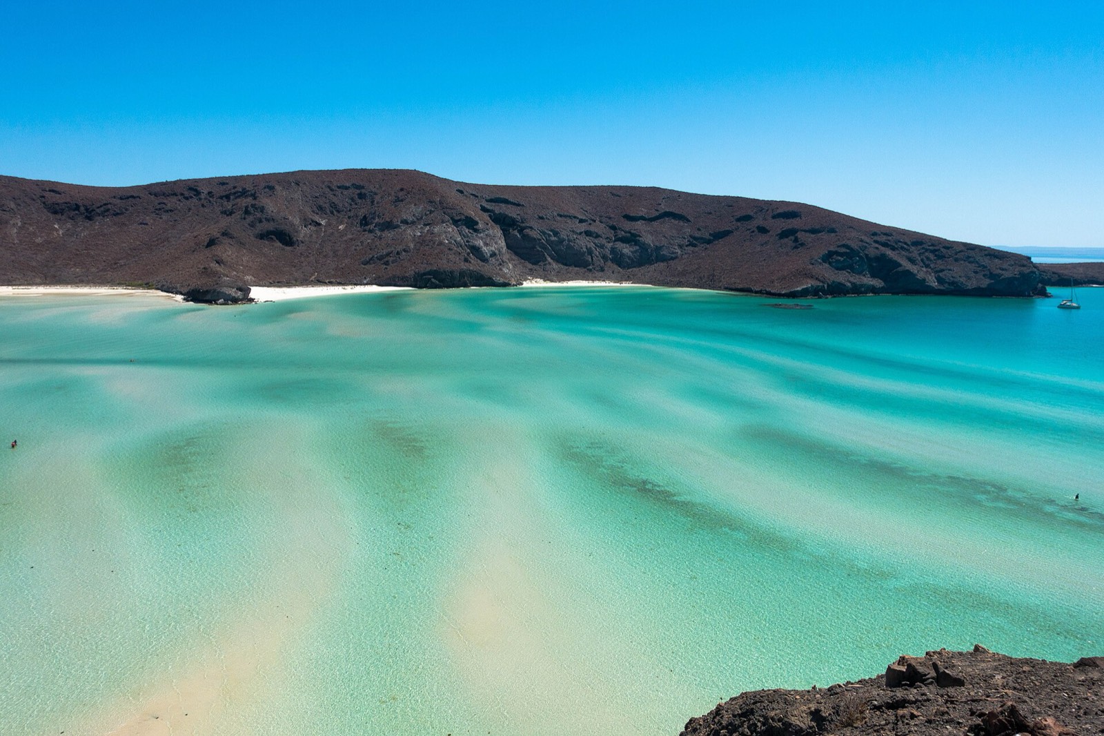 Shallow turquoise lagoon and white sand at Balandra Beach near La Paz, framed by rocky desert hills
