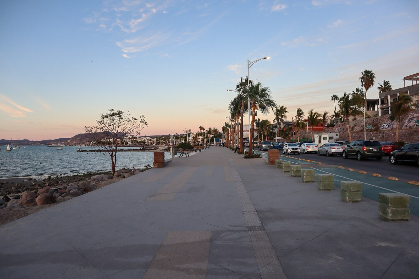 The palm-lined Malecón of La Paz at dusk, with the waterfront promenade running along the bay