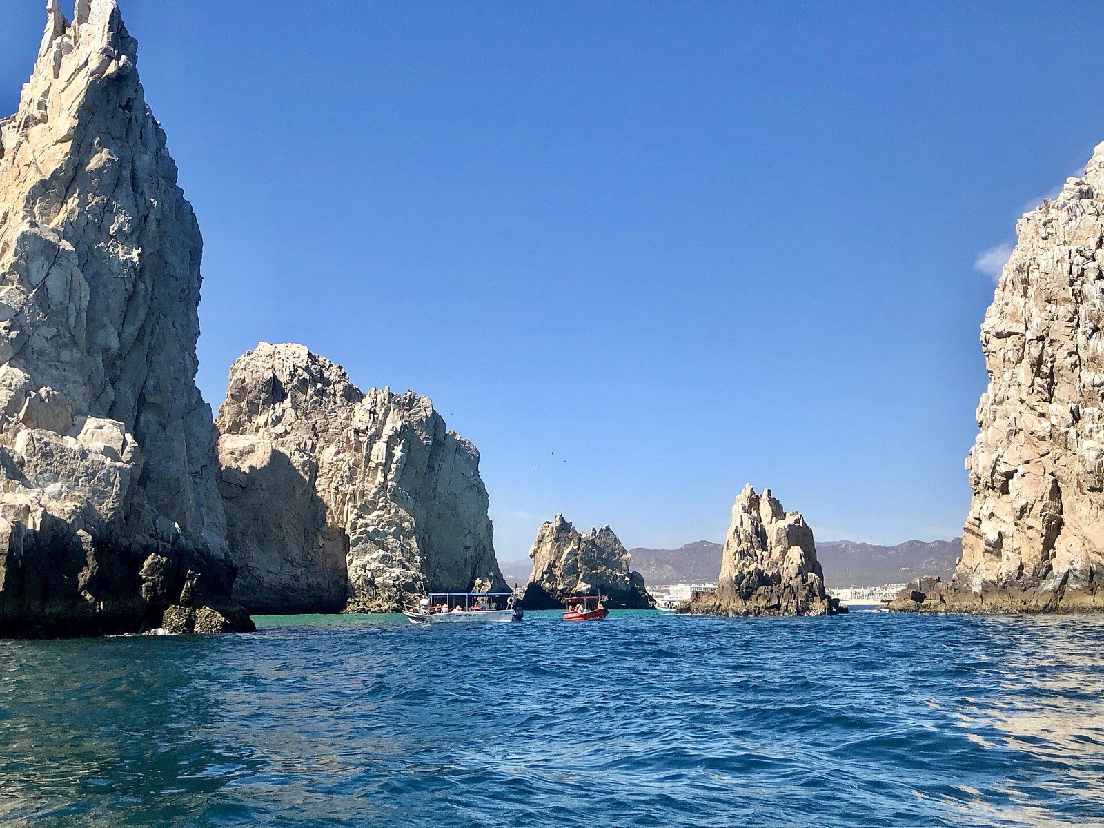 Water taxis motoring between towering granite rocks at Land's End near Lover's Beach in Cabo San Lucas