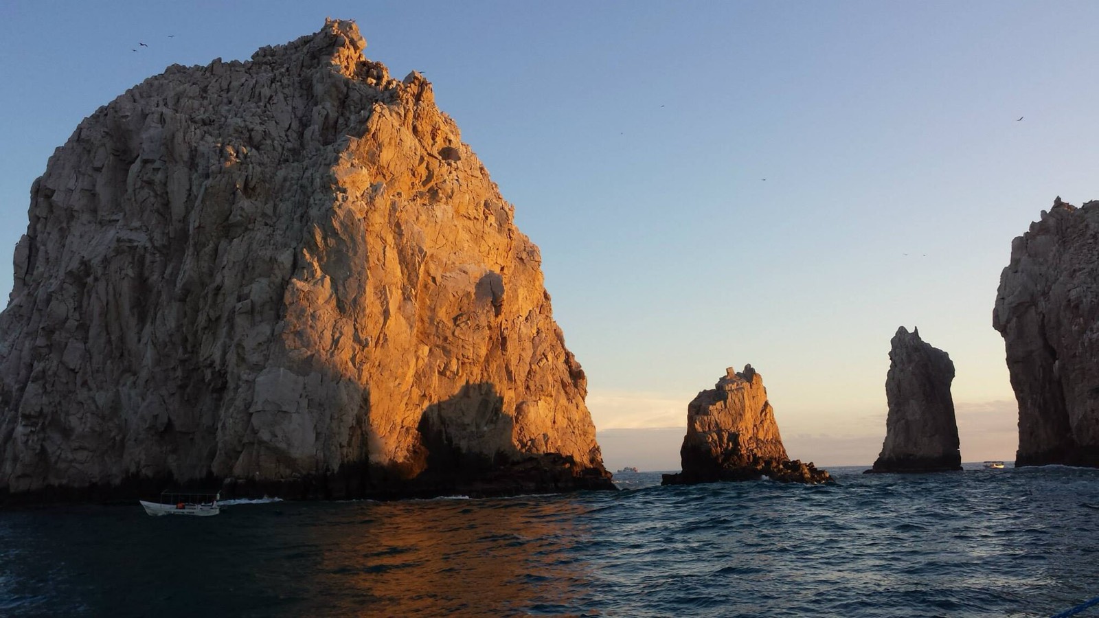 Sunlit granite rock formations at Land's End seen from a boat on the water in Cabo San Lucas