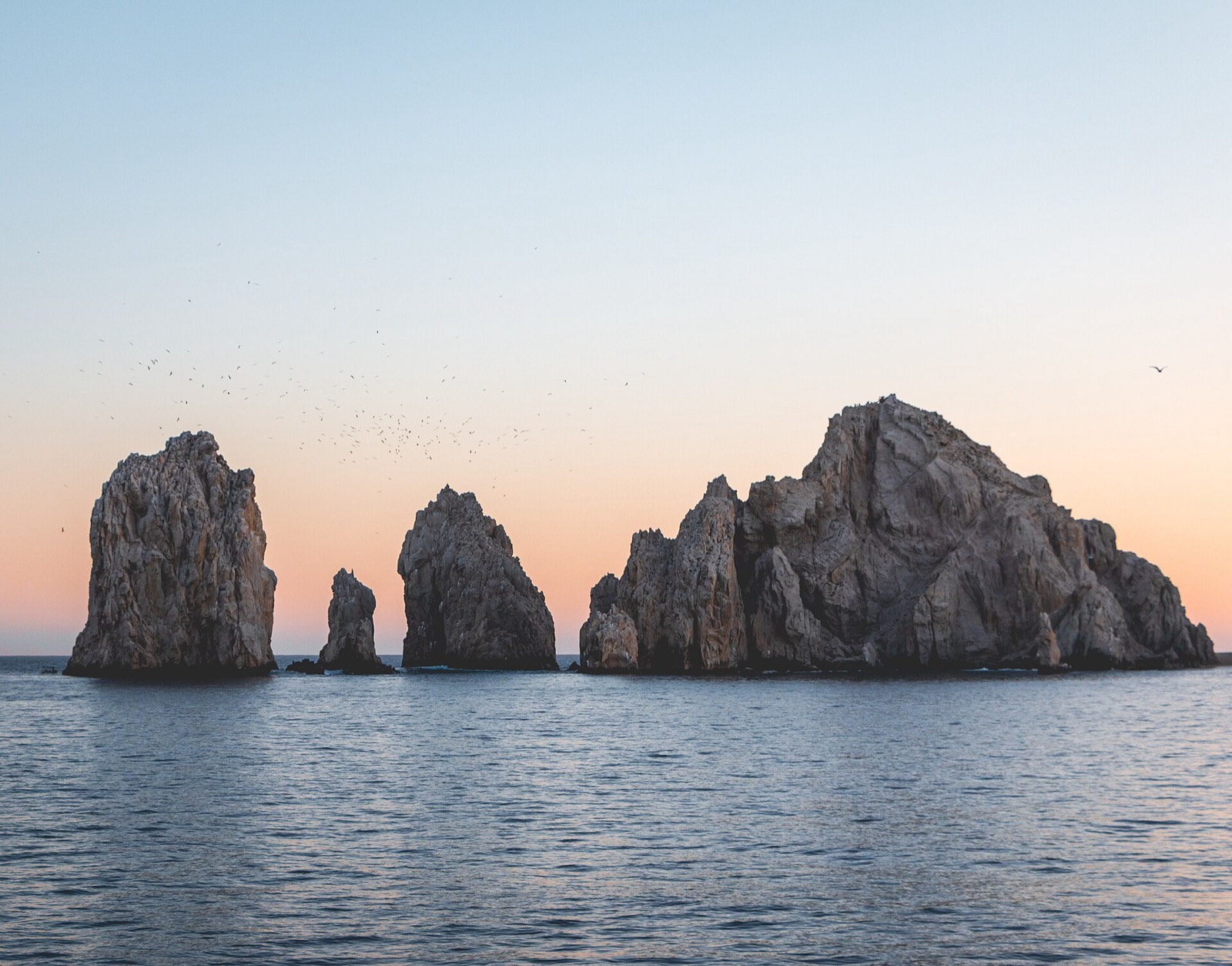 Granite rock formations beside El Arco at Land's End seen from the water at sunset in Cabo San Lucas