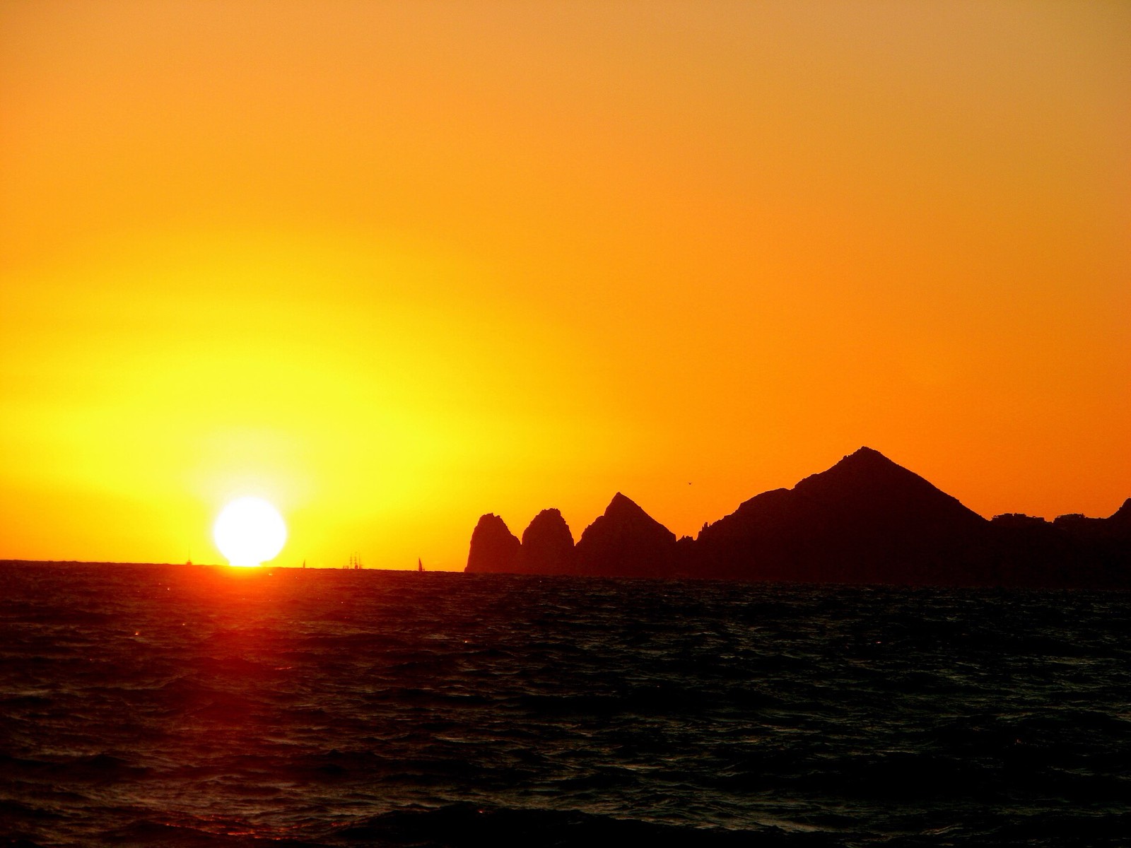 Sun setting over the ocean beside the silhouetted Land's End rocks in Cabo San Lucas