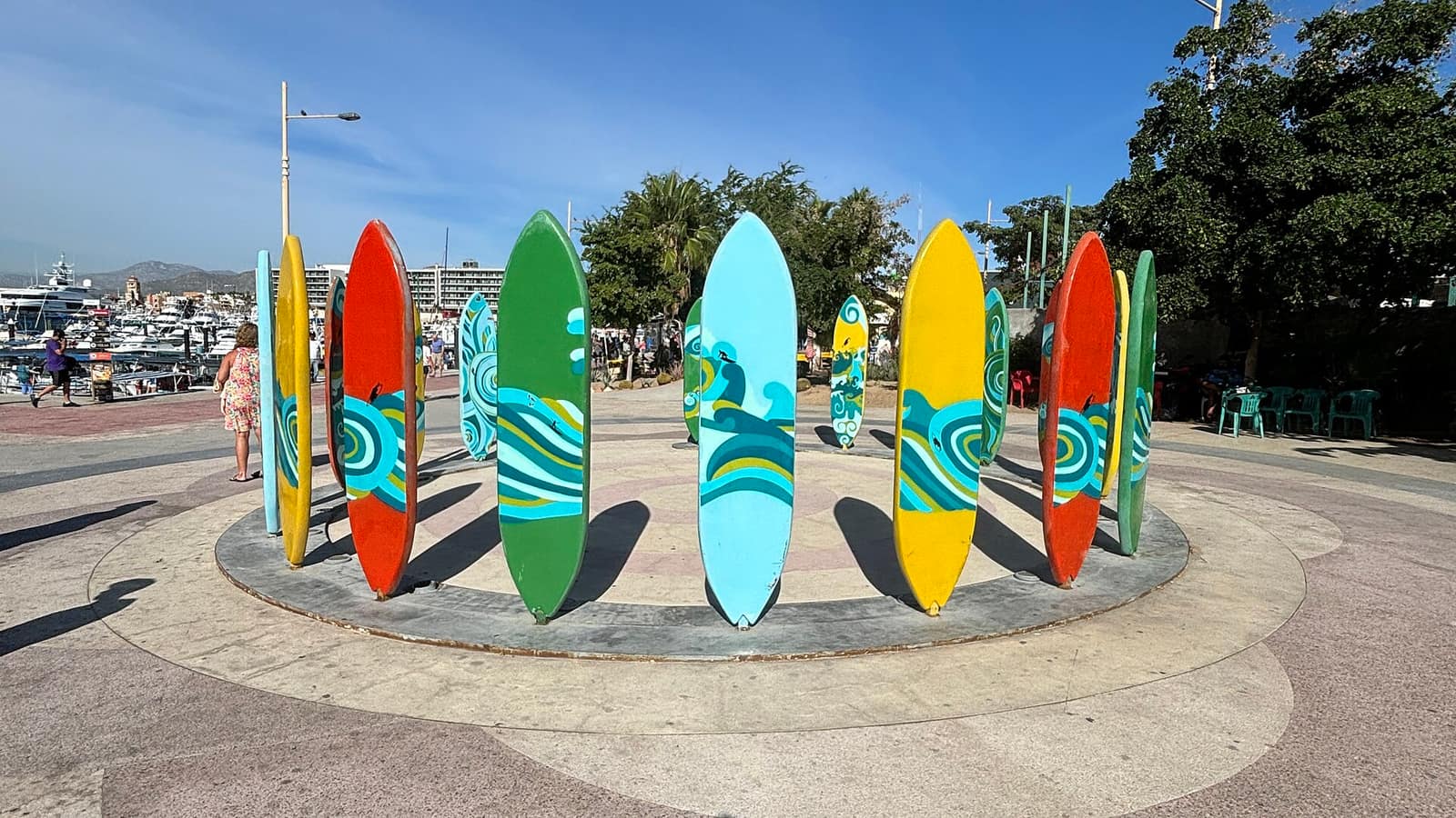 Colorful surfboard sculptures at the Cabo San Lucas marina, with boats docked in the harbor behind